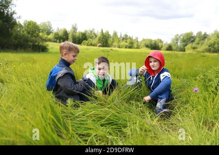 Trois enfants se reposent sur la pelouse en été Banque D'Images