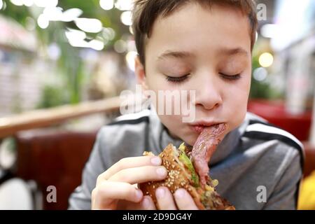 Portrait d'un enfant mangeant un hamburger au restaurant Banque D'Images