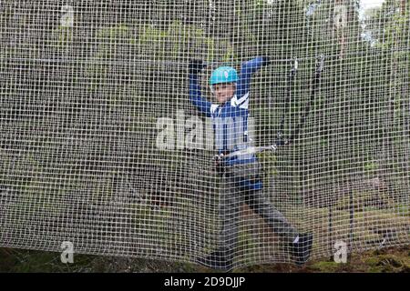 Garçon surmontant un obstacle en mesh dans le parc d'aventure de corde, Karelia Banque D'Images