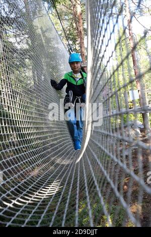 Garçon surmontant l'obstacle de filet dans le parc de corde, Karelia Banque D'Images