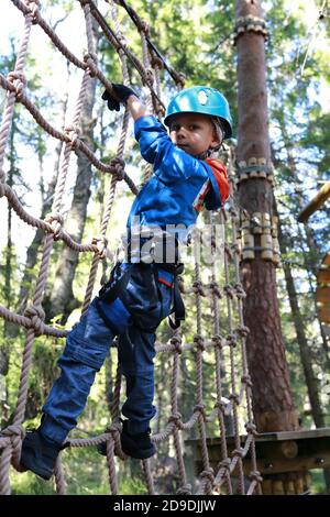 Enfant surmontant l'obstacle du filet dans le parc d'aventure de la forêt, Karelia Banque D'Images