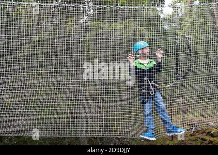Enfant surmontant l'obstacle de filet dans le parc d'aventure de corde, Karelia Banque D'Images
