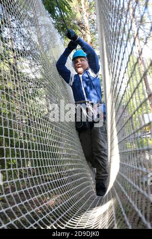 Enfant surmontant l'obstacle de filet dans le parc de corde, Karelia Banque D'Images