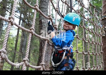 Enfant surmontant l'obstacle de mesh dans le parc d'aventure de forêt, Carélia Banque D'Images