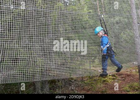 Enfant surmontant l'obstacle de mesh dans le parc d'aventure de corde, Karelia Banque D'Images