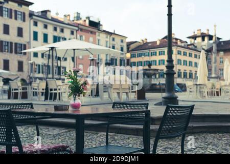 Un pot de fleurs sur une table de café vide en Italie. Le coronavirus force les gens à rester en sécurité à la maison. Udine ville, Friuli Venezia Giulia, Italie. Banque D'Images