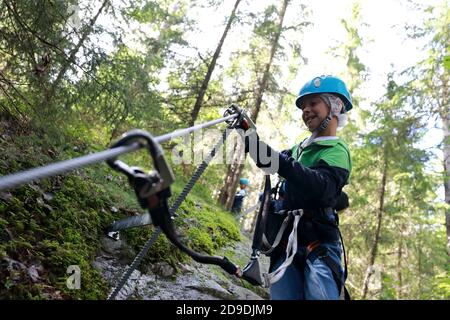 Garçon utilisant le mousqueton sur la route d'entraînement à corde parc, Karelia Banque D'Images