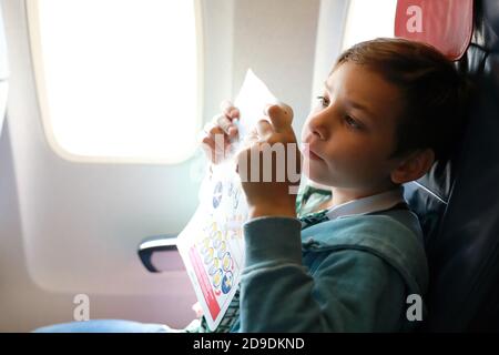 Enfant étudiant les instructions de sécurité de vol à bord de l'avion Banque D'Images