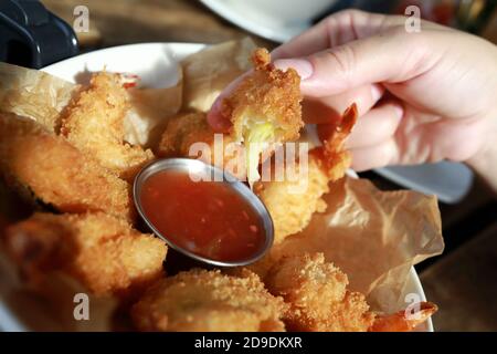 Personne trempant des légumes tempura dans une sauce au restaurant vietnamien Banque D'Images