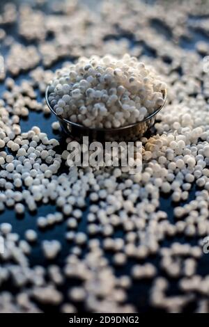 Gros plan de perles de sagou brutes ou de perles de tapioca dans une plaque de verre sur une surface noire. Banque D'Images