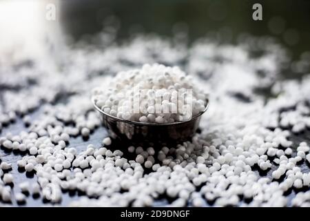Gros plan de perles de sagou brutes ou de perles de tapioca dans une plaque de verre sur une surface noire. Banque D'Images