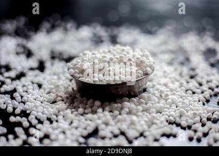 Gros plan de perles de sagou brutes ou de perles de tapioca dans une plaque de verre sur une surface noire. Banque D'Images