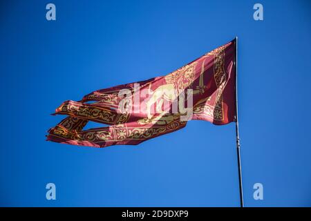 Drapeau rouge de Venise avec lion d'or et épée dans l'air sur un ciel bleu Banque D'Images