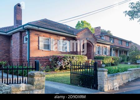 Une maison de l'entre-deux-guerres en brique double et carrelage au toit de Gordon, Sydney, Australie avec une entrée portique en brique ornée et une clôture avant en pierre taillée à la main Banque D'Images