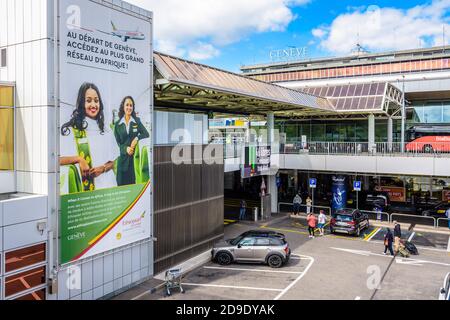 Vue générale de l'entrée principale de l'aéroport international de Genève (GVA) avec les passagers qui montent jusqu'au hall sur le parking ci-dessous. Banque D'Images