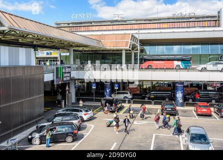 Vue générale de l'entrée principale de l'aéroport international de Genève (GVA) avec les passagers se passant l'un l'autre sur le parking ci-dessous. Banque D'Images