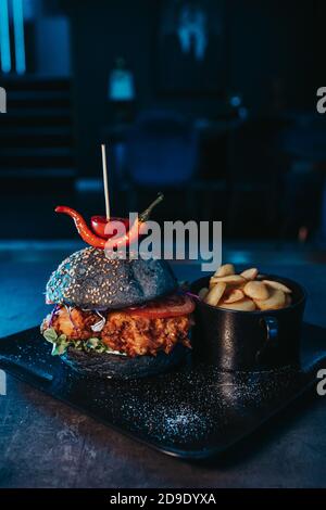 Photo sélective d'un savoureux hamburger noir à la française frites dans un bol Banque D'Images
