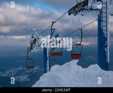 Remontée mécanique de la station de ski alpin avec places au-dessus du coucher du soleil pistes de ski de montagne par temps extrêmement venteux Banque D'Images