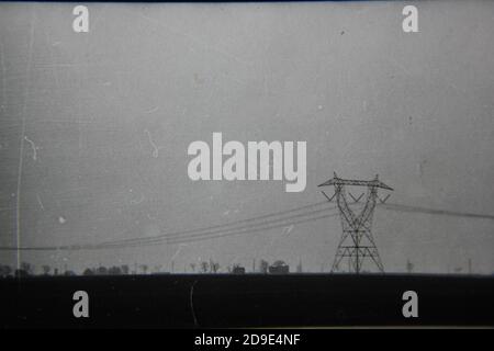 Belle photographie en noir et blanc vintage des années 1970 du brouillard et des lignes électriques vues sur la route lors d'un trajet matinal dans le pays. Banque D'Images