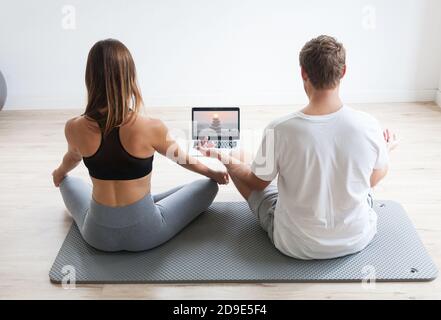 couple sportif dans les vêtements de sport méditant l'utilisation d'un ordinateur portable à la maison Banque D'Images