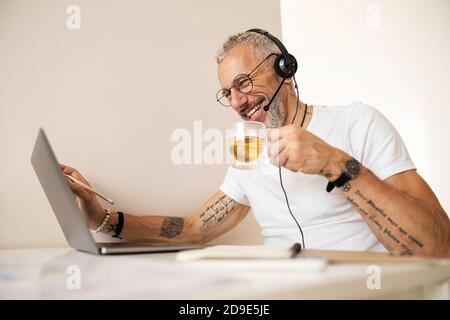 Travailleur avec des bras tatoués buvant du thé et touchant l'écran Banque D'Images