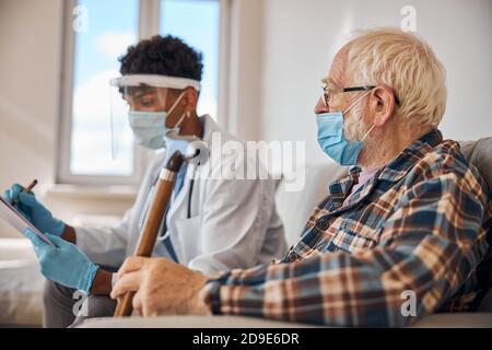 Homme âgé dans un masque regardant un médecin Banque D'Images