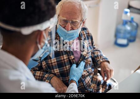 Professionnel de la santé auscultant l'homme âgé de race blanche Banque D'Images