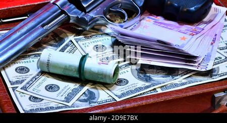 Valise de concept de vol plein de dollars volés Revolver Smith e Wesson 357 manum sur un fond de dollars de 100 dollars de billets de banque Banque D'Images