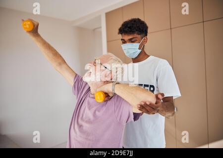 Poids de levage homme senior soutenu par un instructeur Banque D'Images