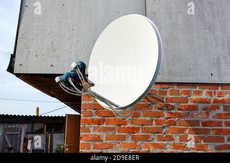 La parabole satellite est fixée au mur de la maison. Une installation de télévision par satellite sous le toit Banque D'Images