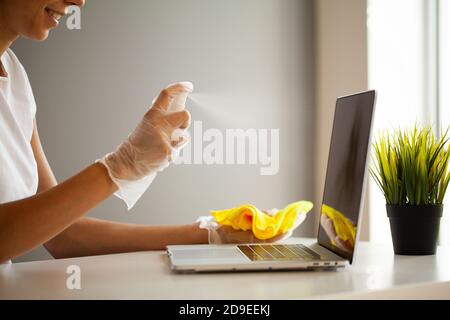 Une femme désinfecte l'ordinateur portable et le smartphone par des lingettes humides et antiseptiques Banque D'Images