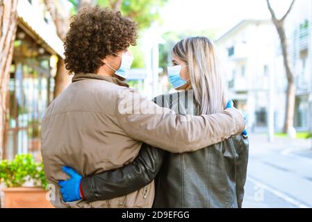 groupe d'un homme mauricien latino et d'une femme blonde caucasienne marchant dans la rue en portant un masque facial et des gants de protection après la réouverture du verrouillage. Banque D'Images