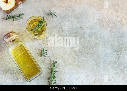 Cidre de pomme ou de poire en grand verre et bouteille de romarin, cannelle et chips de fruits secs, fond en béton léger. Vue de dessus. Banque D'Images