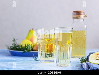 Cocktail au cidre de poire avec romarin dans de grands verres et bouteille et poires fraîches, fond en pierre bleue. Boissons rafraîchissantes en été. Banque D'Images