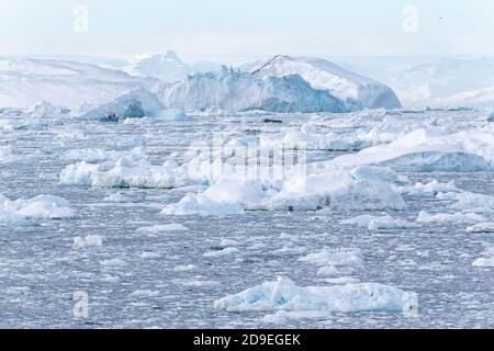 Un bateau Fisher navigue entre des icebergs colossaux dans la mer arctique. Disko Bay, Ilulissat, Groenland Banque D'Images