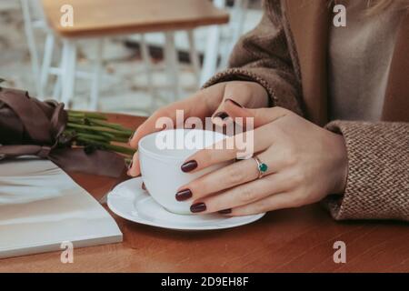 Portrait sans visage d'une jeune femme élégante qui boit le café du matin assis sur le café en plein air dans le centre-ville. Détails de la mode d'automne Banque D'Images