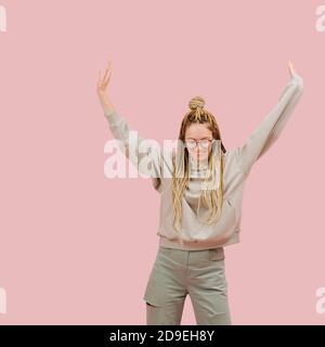 Bonne dansante femme dans des verres avec blonde élégant braid afro sur rose Banque D'Images