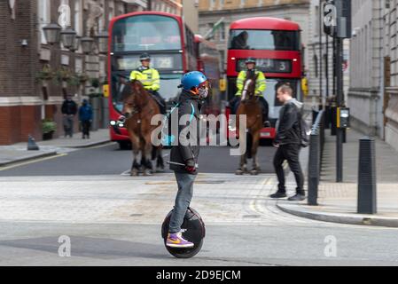 Westminster, Londres, Royaume-Uni. 5 novembre 2020. Le premier jour du second confinement au Royaume-Uni a vu des rues plus calmes, mais pas vides, à Londres. Les gens font de l'exercice ou font du déplacement. La police se prépare à une manifestation anti-verrouillage prévue et est en nombre. La police montée regarde un pilote de monocycle électrique passer sur Whitehall Banque D'Images