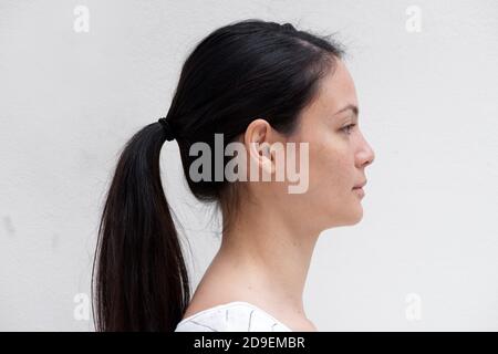 Gros plan portrait de profil jeune femme asiatique avec une expression sérieuse sur fond blanc Banque D'Images