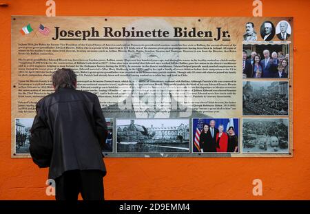 Un homme s'arrête pour lire une plaque sous une fresque du candidat à la présidence des États-Unis Joe Biden dans sa maison ancestrale de Ballina, Co. Mayo, Irlande, où il s'est rendu en juin 2016 en tant que vice-président. Banque D'Images