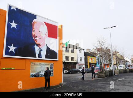 Un homme s'arrête pour lire une plaque sous une fresque du candidat à la présidence des États-Unis Joe Biden dans sa maison ancestrale de Ballina, Co. Mayo, Irlande, où il s'est rendu en juin 2016 en tant que vice-président. Banque D'Images