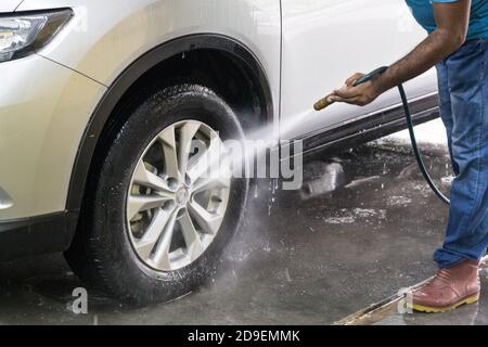 L'employé vaporise de l'eau sur la voiture pour la laver Banque D'Images