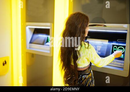 Femme afro-américaine qui retire de l'argent d'un distributeur automatique de billets, concept ATM. Banque D'Images