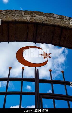 Symbole musulman demi-lune et étoile sur fond de ciel et de nuages. Arc et grille de clôture. Banque D'Images