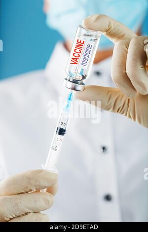 Le médecin tient avec des gants de protection et un masque tient l'ampoule avec le vaccin. Banque D'Images