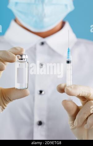 Ampoule et seringue dans les mains d'un médecin chercheur en gants de caoutchouc avec un gros plan sur le vaccin et espace libre pour le texte sur l'autocollant de l'ampoule. Banque D'Images