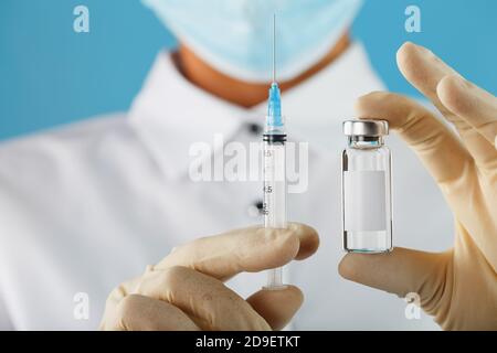 Ampoule et seringue dans les mains d'un médecin chercheur en gants de caoutchouc avec un gros plan sur le vaccin et espace libre pour le texte sur l'autocollant de l'ampoule. Banque D'Images