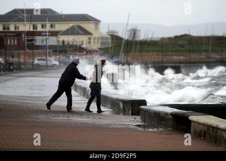 Prestwick Promenade.Ayrshire, Écosse, Royaume-Uni les gens appréciant la promenade de tempête écrasée.Deux adolescents risquent de se faire tremper par les vagues qui se brisent Banque D'Images