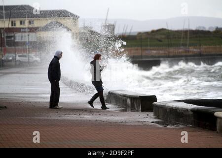 Prestwick Promenade.Ayrshire, Écosse, Royaume-Uni les gens appréciant la promenade de tempête écrasée.Deux adolescents risquent de se faire tremper par les vagues qui se brisent Banque D'Images