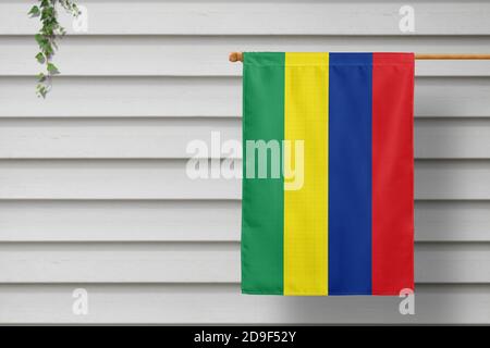 Le petit drapeau national mauricien est suspendu d'une clôture de piquetage le long du mur en bois d'une ville rurale. Concept de jour d'indépendance. Banque D'Images